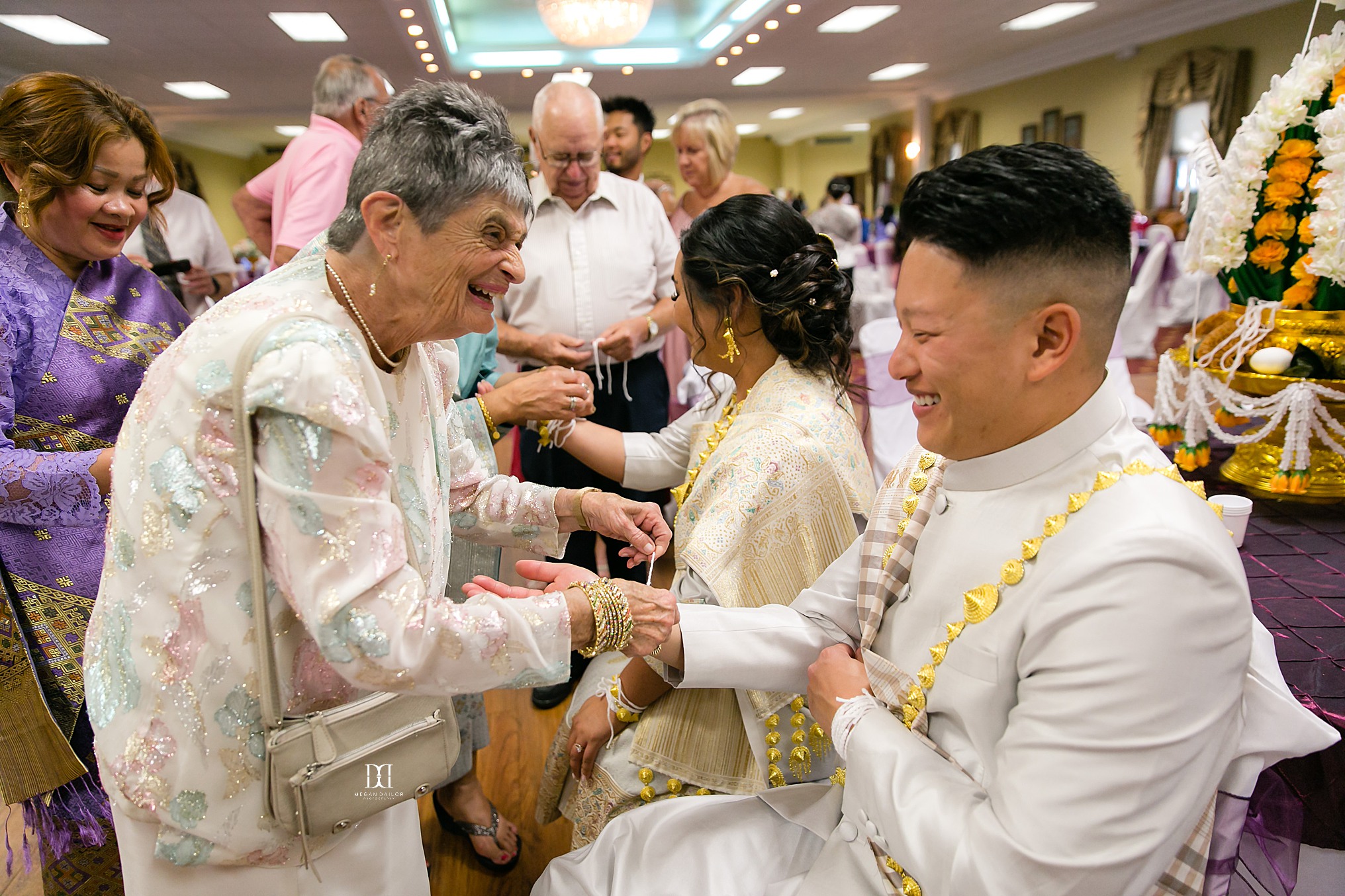 trying a string around bride and grooms wrists to signify wishes for the couple rochester photographers