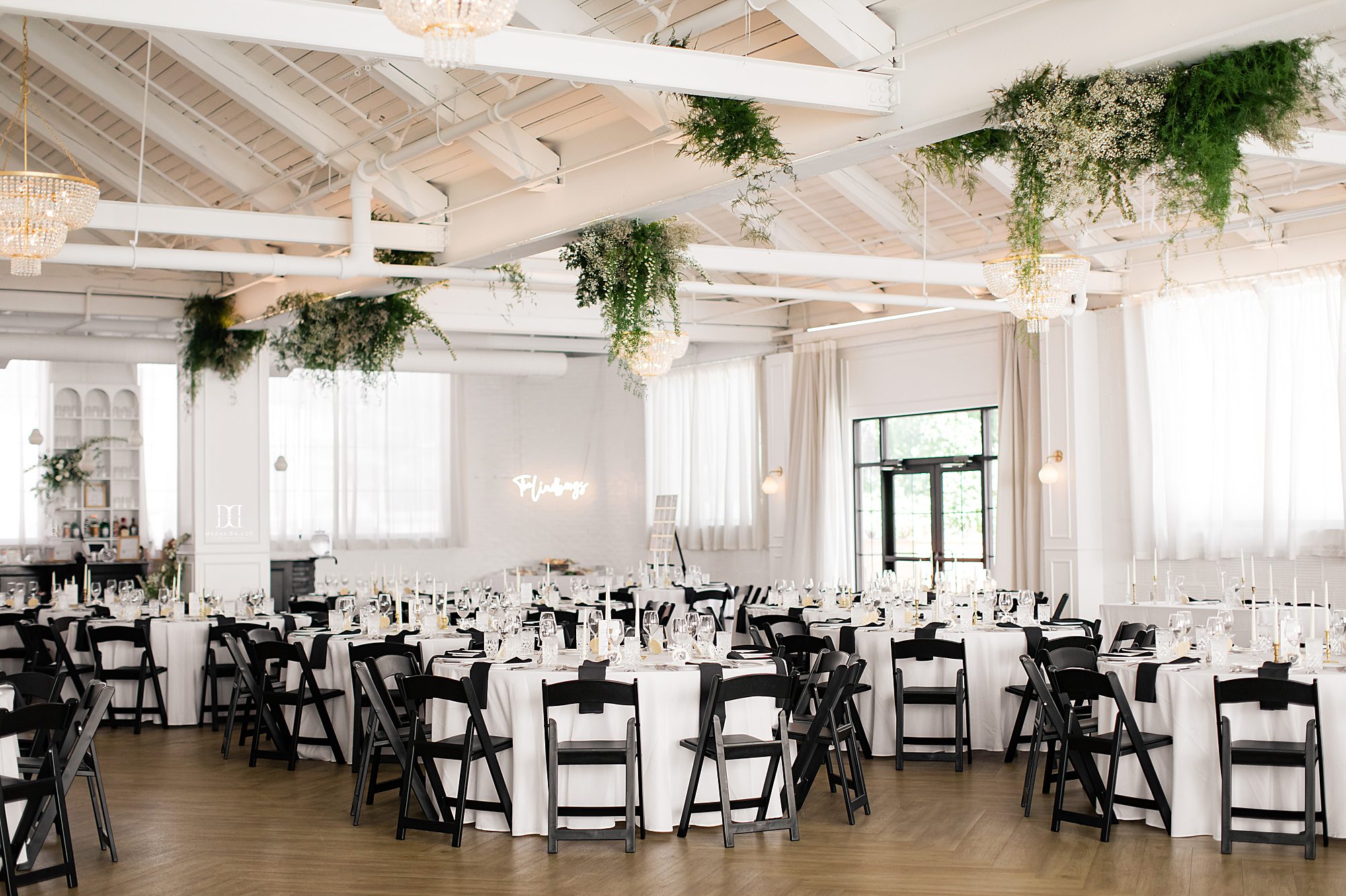 weddings at the highline ballroom decorated with white linens black chairs and greenery